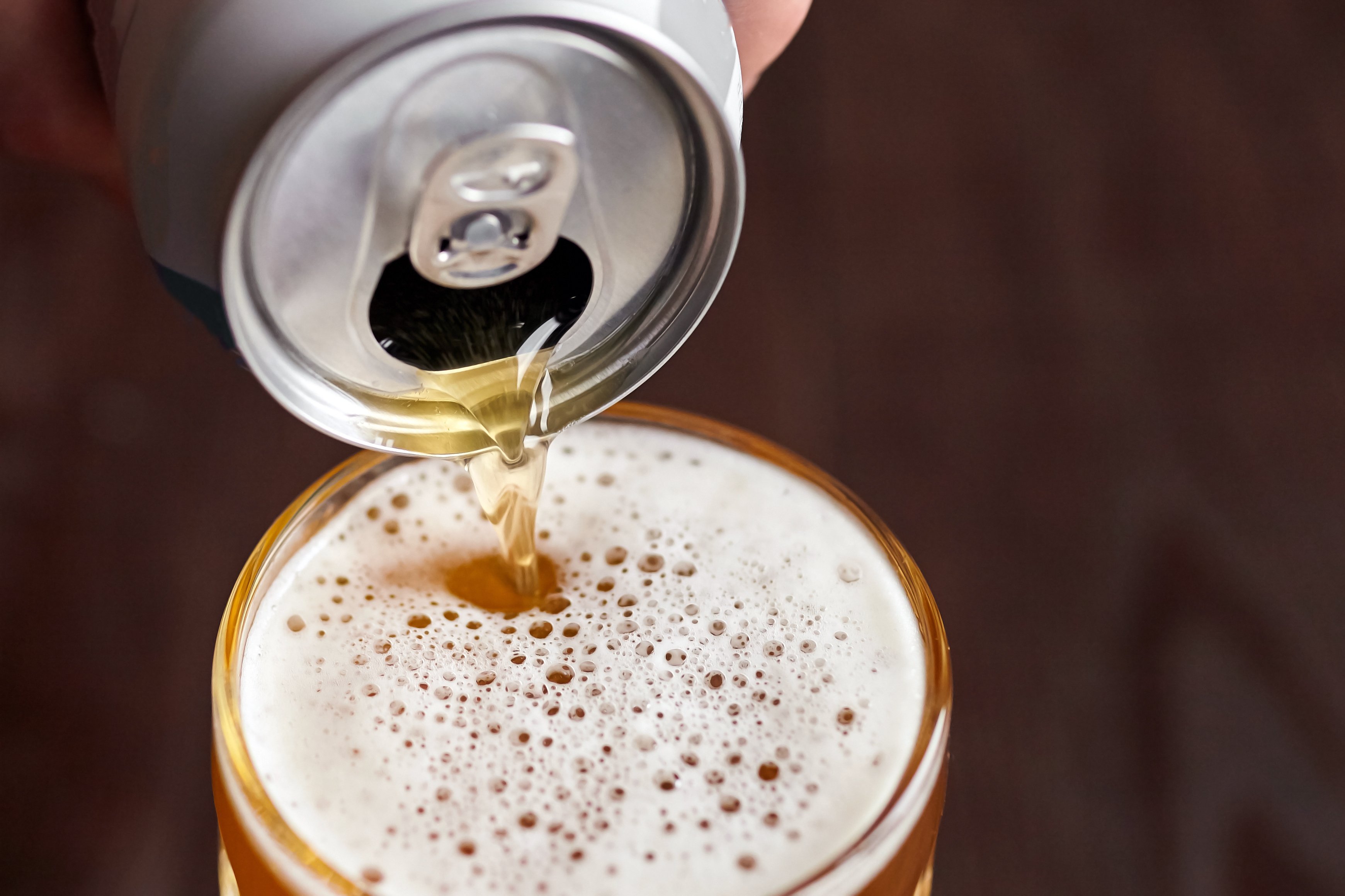 A can of beer pouring into a glass.