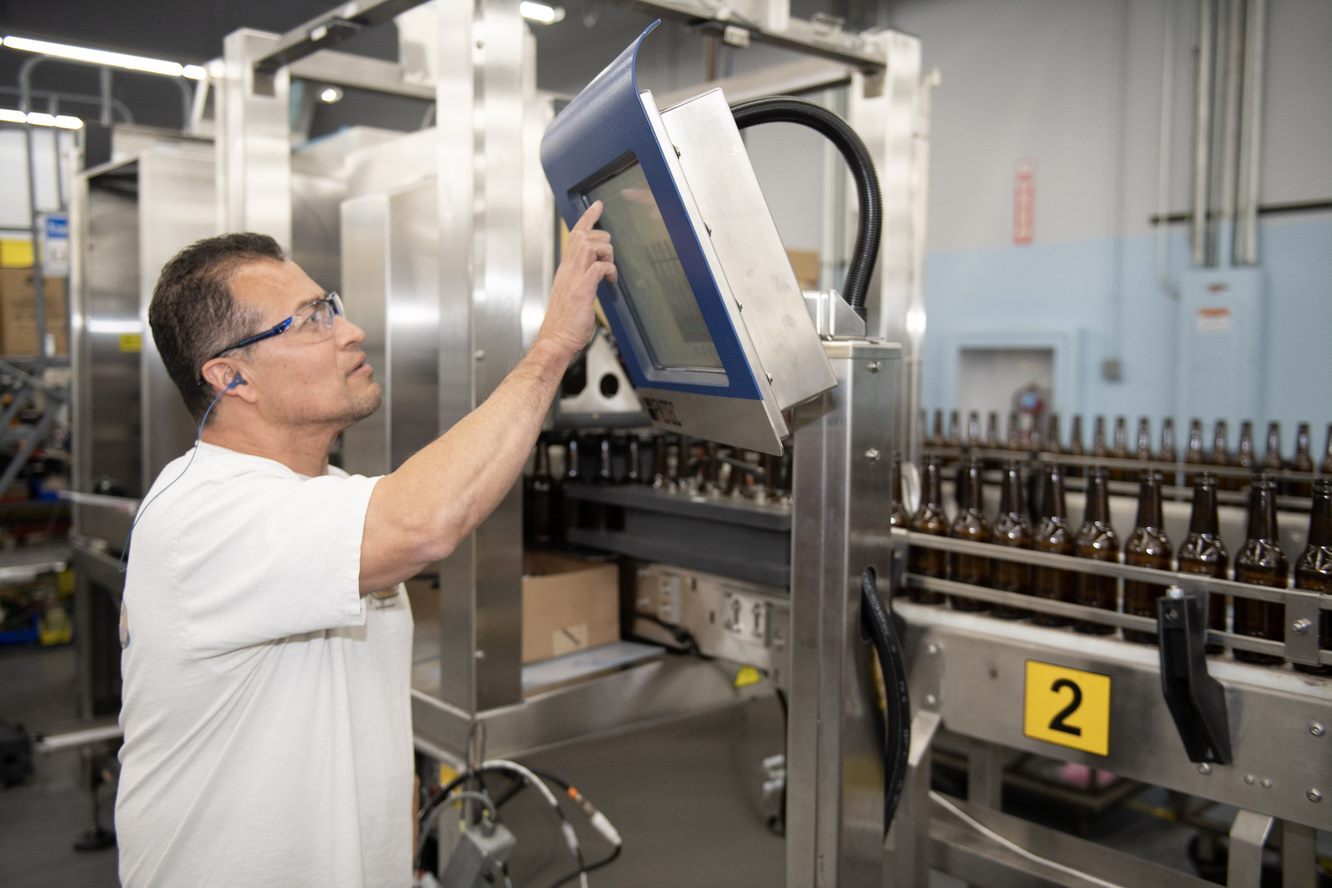 A man works with machinery on a bottling line